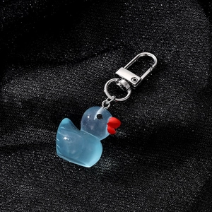 Macro detail of translucent blue resin duck charm with metallic silver keyring and hook