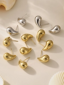 Macro shot of polished gold and silver teardrop earrings with smooth mirror finish