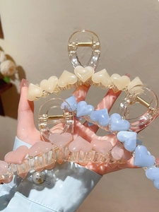 Close-up of translucent heart claw clips in beige, light blue, and soft pink shades