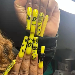 Detail of long yellow press-on nails featuring luxury patterns and 3D bear decoration