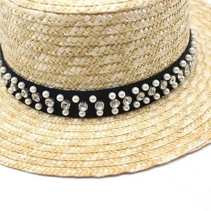 Chapeau de paille à sommet plat avec ruban noir orné de perles et strass scintillants