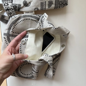 Detail of vintage paisley print canvas bag interior showing metal magnetic buckle and pocket