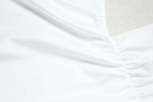 Detail view of white ruched fabric with premium sheen and elastic texture on dress