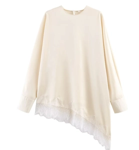 Détail de la blouse en satin beige avec empiècement en dentelle blanche irrégulière au bas