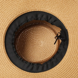 Detail view of woven straw hat interior featuring black sweatband and adjustable string