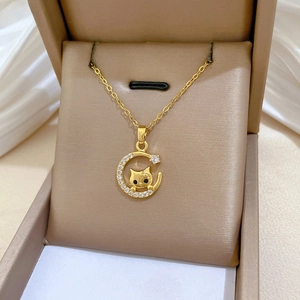 Macro shot of gold moon and cat pendant with pavé cubic zirconia on jewelry box