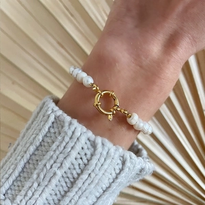 Baroque natural freshwater pearl bracelet with a golden clasp on a knitted sweater background