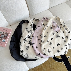 Detail view of four large canvas tote bags with butterfly prints on a white soft sofa