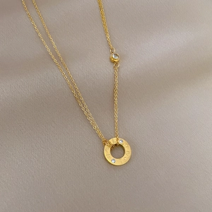 Macro detail of gold-plated double-layer necklace with screw motif pendant and zircon stones