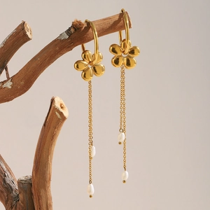Detailed view of 18K gold plated flower earrings with pearl tassels on wooden branch
