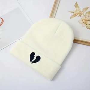 Minimalist cream knit beanie featuring a black embroidered broken heart on a wide cuff
