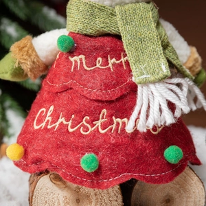 Plush Christmas doll decoration in red felt dress with green scarf on a wooden base