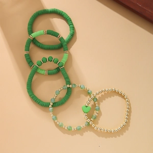 Detail of 5-piece green and gold bohemian bead bracelet set with clay discs and heart charms