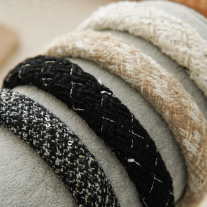 Close-up of four tweed headbands in black, beige, and white with textured woven fabric