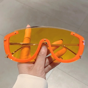 Macro view of bright orange oversized shield sunglasses with translucent yellow lenses