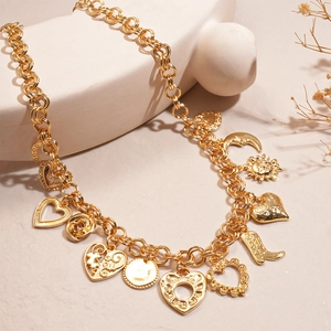 Gold charm necklace featuring heart moon and sun pendants on a minimalist display