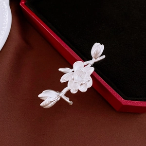 Gros plan sur la broche fleur de magnolia en argent mat sur du velours marron