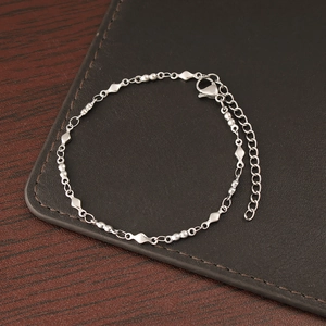 Detail of silver geometric link bracelet with lobster clasp on leather background