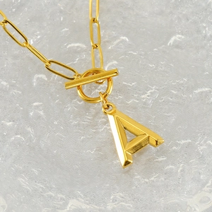 Macro shot of gold OT buckle necklace with 3D letter A pendant on paperclip chain