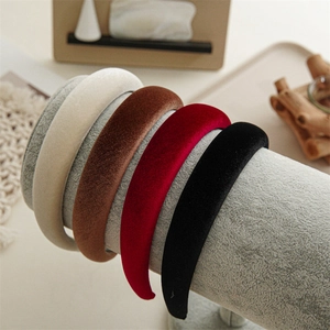 Detail of padded velvet headbands in cream, brown, burgundy, and black displayed on a rack