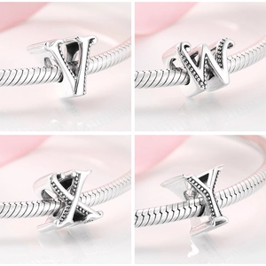 Macro detail of S925 sterling silver alphabet charms V, W, X, Y on a snake chain bracelet