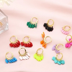 Détail de boucles d'oreilles créoles à pampilles cœur sur tissu rose texturé