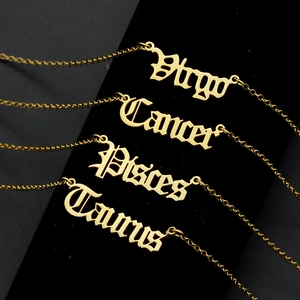 Close-up of gothic font zodiac signs necklaces in gold plating on black velvet background