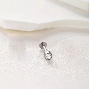 Macro shot of silver titanium labret stud with a clear round crystal and water drops