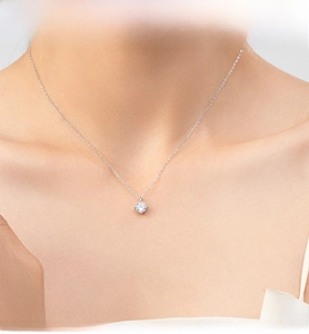 Macro close-up of a brilliant round-cut solitaire diamond pendant on a silver thin chain