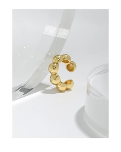Detail of golden S925 silver clip-on earring with textured beaded surface on acrylic stand