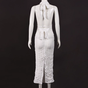 Back view of a white backless halter maxi dress with textured fabric and slit detail