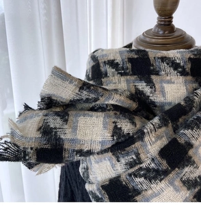 Detailed view of the thick houndstooth scarf texture with fine fringe on a wooden mannequin