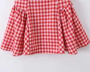 Détail de l'ourlet de la robe vichy rouge avec volants et texture du tissu coton