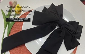 Macro detail of large black satin multi-layer bow hair clip with long elegant ribbons