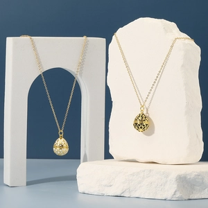 Elegant gold egg pendants with black and white enamel on a minimalist stone display