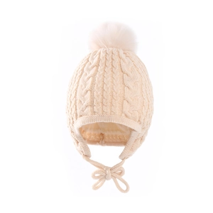 Close-up of knit texture and pom-pom detail on beige baby earflap winter hat