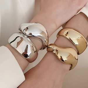 Macro di bracciali geometrici irregolari sovrapposti in finiture oro e argento lucido