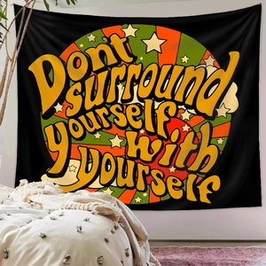 Detail of a black Bohemian tapestry with a vintage sun star quote on a bedroom wall