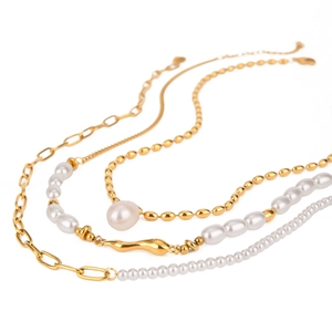 Layered gold stainless steel necklace featuring white freshwater pearls on white background