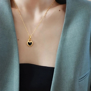 Elegant gold titanium steel necklace with a beaded black heart pendant on a model