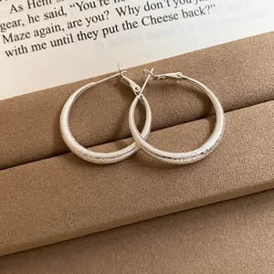 Detail of silver matte hoop earrings with frosted finish on brown velvet stand