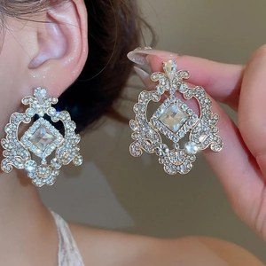 Détail de boucles d'oreilles dorées avec cristaux et motifs géométriques sur modèle
