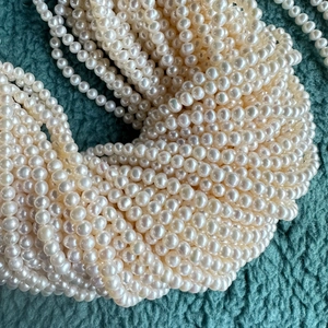 Macro shot of 4-5mm natural white freshwater pearls clustered on dark green fabric