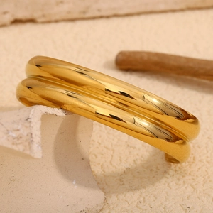 Dettaglio di un bracciale rigido largo a doppio strato placcato oro 18 carati su marmo