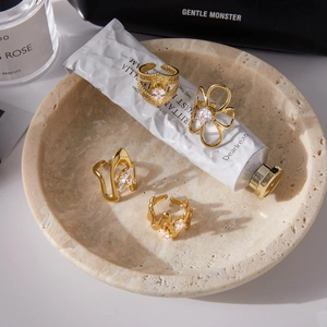 Detalle de cuatro anillos ajustables bañados en oro con circonitas en bandeja de mármol