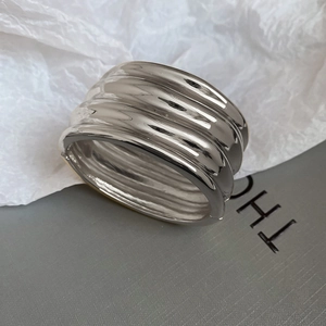 Macro detail of glossy silver metal bangle with elegant irregular wave texture