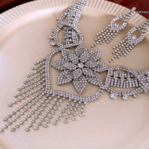 Detailed macro view of silver rhinestone heart necklace with tassel and matching earrings