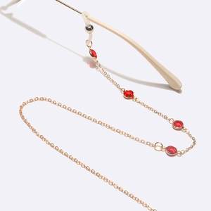 Detail of golden glasses chain with red crystal accents and rubber grip connectors