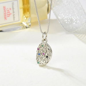 Detailed close-up of a silver pebble-shaped pendant with multi-colored gemstones on a box chain