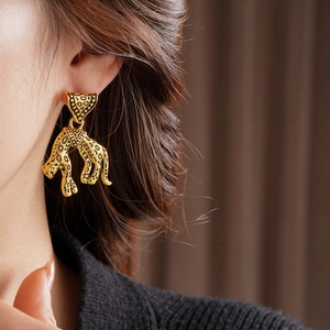 Macro shot of vintage leopard leopard head earring with triangle drop in antique gold finish